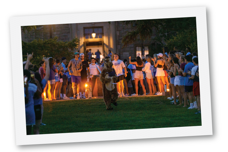 Students gathered around the camel mascot in the evening