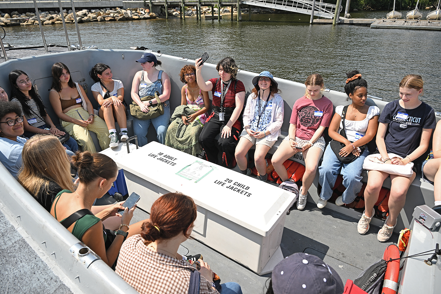 A group of students gather on bench seats in a water taxi.