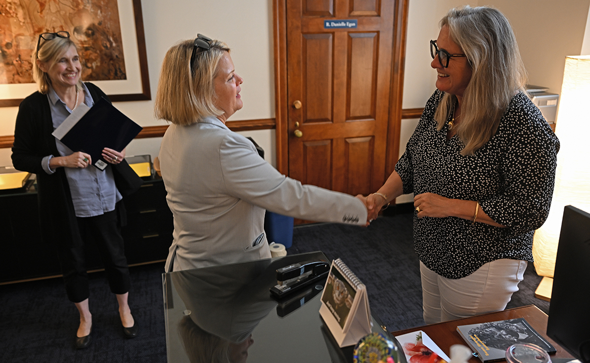 College president shakes hands with staffer during welcome tour