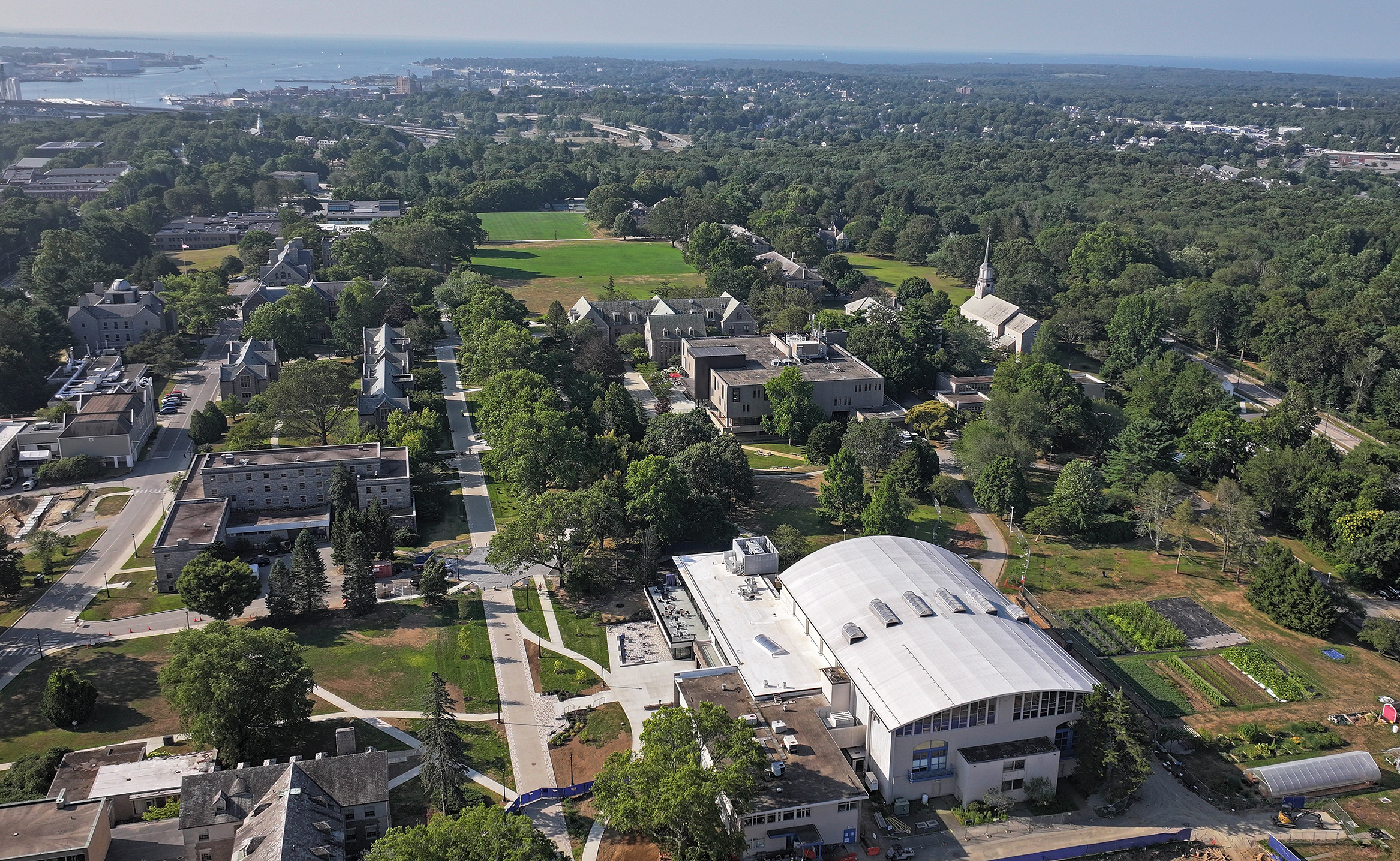 Aerial view of a lightly wooded college campus looking south toward the shoreline.