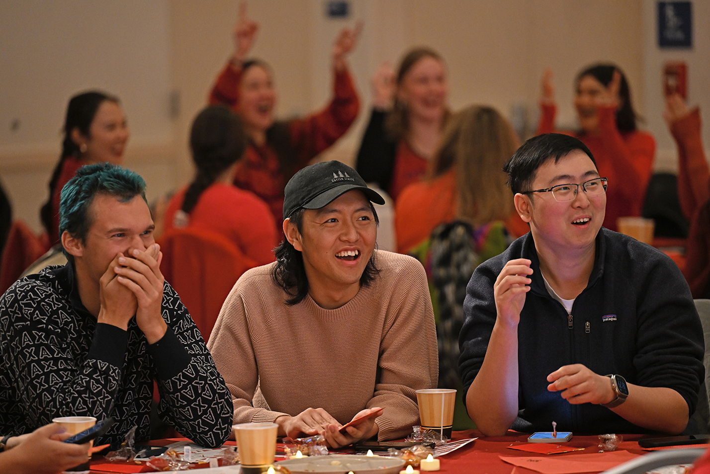 Students gather around large round tables to socialize during a Lunar New Year celebration.